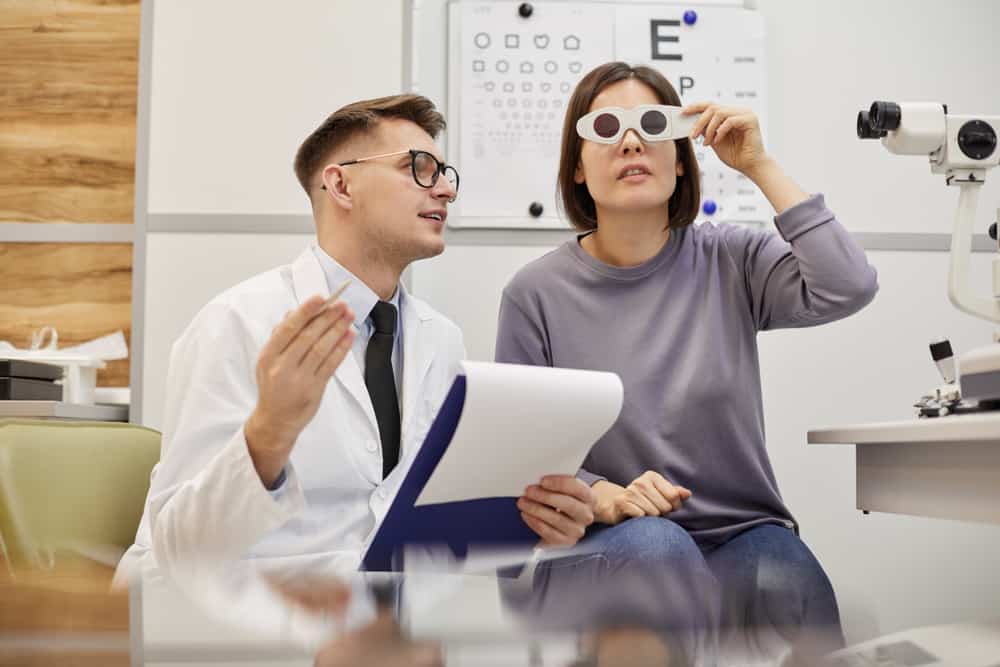 Young Optometrist Talking To Young Woman During Vision