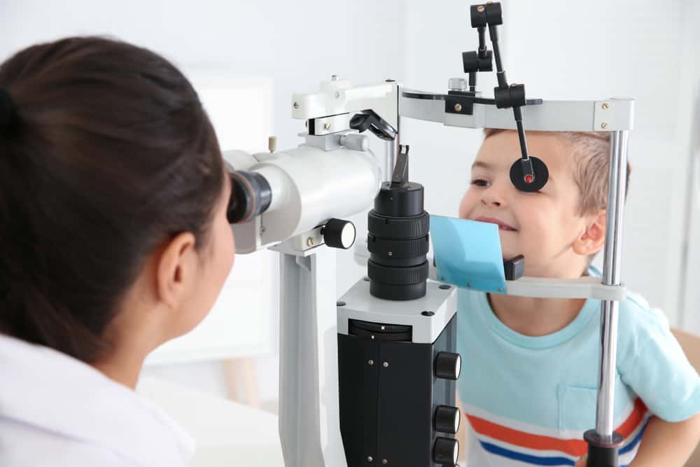 Doctor Examining Little Boy With Ophthalmic Equipment In Clinic